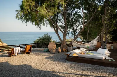 a hammock with a table and chairs and the ocean at Ninémia Sea living in Archangelos