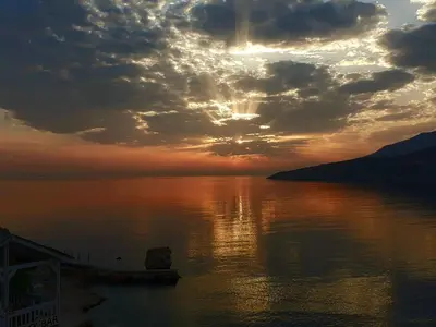 a sunset over a body of water with the sun setting at ILIDI Rock in Livadia