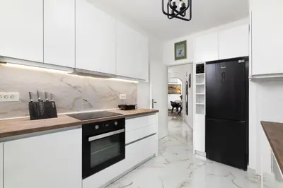 a kitchen with white cabinets and a black refrigerator at Le Peridot Garden House in Rhodes Town