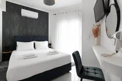 a bedroom with a white bed and a black chair at Le Peridot Garden House in Rhodes Town