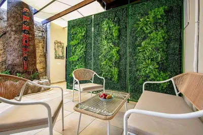 a patio with chairs and a green wall at Old Town Corner Luxury Studios in Rhodes Town