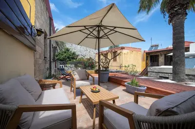 a patio with chairs and a table with an umbrella at Old Town Corner Luxury Studios in Rhodes Town