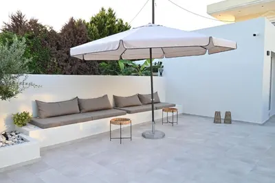 a patio with a couch and an umbrella at Rhotheon Suites in Ialysos Rhodes - private pool in selected rooms in Ialyssos