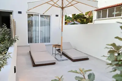 a patio with two chairs and an umbrella at Rhotheon Suites in Ialysos Rhodes - private pool in selected rooms in Ialyssos