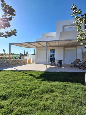 a white house with a table and chairs in a yard at Almira Beach House in Kiotari