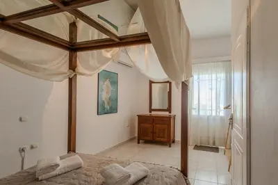 a bedroom with a canopy bed and a dresser at STEGNA REA Seaside Apartment in Archangelos