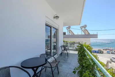 a balcony with tables and chairs and a view of the ocean at STEGNA REA Seaside Apartment in Archangelos