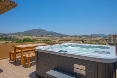 a hot tub on a balcony with a table at Asimenis Cottages in Kattavía