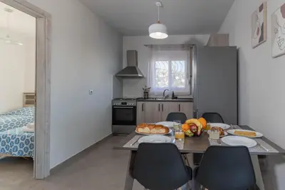 a kitchen with a table and chairs with food on it at Aegean Sunrise View in Archangelos