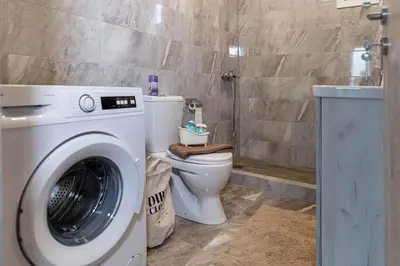 a bathroom with a washing machine and a toilet at Aegean Sunrise View in Archangelos