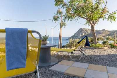 a patio with a table and chairs and the ocean at Aegean Sunrise View in Archangelos