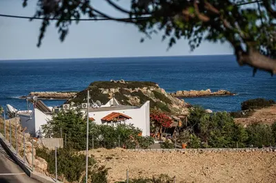 a white building on a hill next to the ocean at Aegean Sunrise View in Archangelos