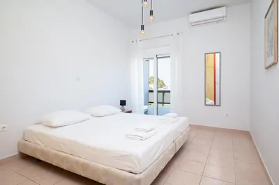 a white bedroom with a large bed with white sheets at Berry apartment in Ixia