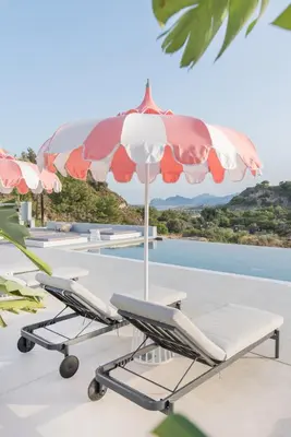 an umbrella and lounge chairs on a patio at The Palms Concept Hotel Adults Only 16 Plus in Faliraki
