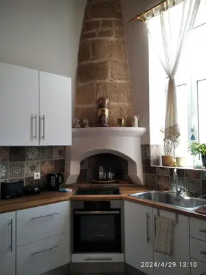 a kitchen with white cabinets and a brick oven at Flora's Traditional House in Malona Village