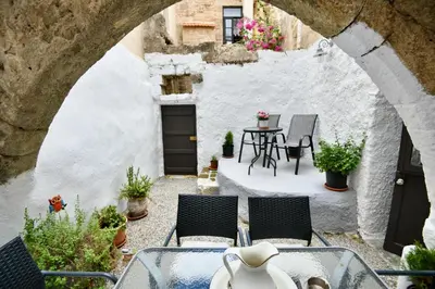 an outdoor patio with chairs and a table in a building at PENELOPE garden house old town in Rhodes Town