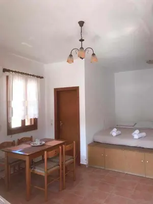 a room with a table and a bed and a table and chairs at Dimitras Studio in Arnítha