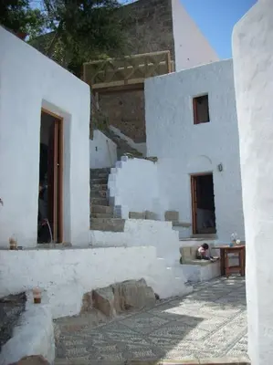 a white building with a dog sitting in front of it at Lindos Traditional House in Rhodes Town