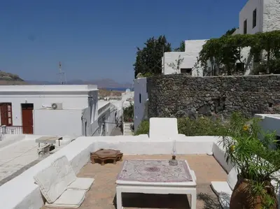 a patio with white furniture and a stone wall at Lindos Traditional House in Rhodes Town