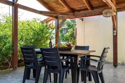 an outdoor dining table and chairs under a wooden pergola at Ibiscus Cottage in Paradisi near the Beach in Paradeísion