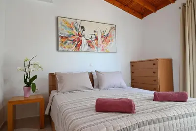 a bedroom with a bed and a painting on the wall at Ibiscus Cottage in Paradisi near the Beach in Paradeísion