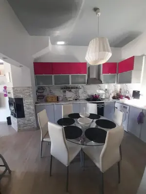 a kitchen with a table with white chairs and red cabinets at Isaias house in Rhodes Town