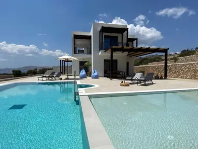 a villa with a swimming pool in front of a house at Pefkos Vista Luxury Villas in Pefki Rhodes