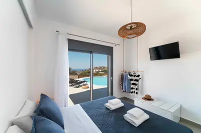 a bedroom with a bed and a view of a pool at Pefkos Vista Luxury Villas in Pefki Rhodes