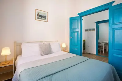 a bedroom with a large bed with blue doors at Galini & Serena Apartments in Symi