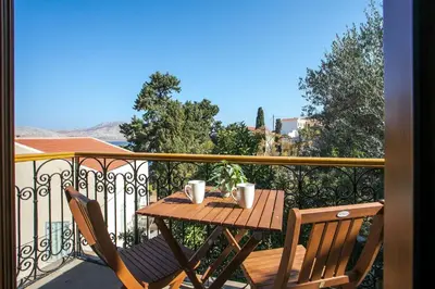 a wooden table with two cups on a balcony at Galini & Serena Apartments in Symi