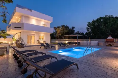 a villa with a swimming pool in front of a house at Villa Dana in Ixia