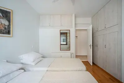 a white bedroom with two beds and a mirror at Plumeria Alba Apartment in Rhodes Town