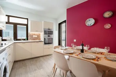 a kitchen with a wooden table and a red wall at Plumeria Alba Apartment in Rhodes Town