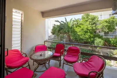 a balcony with pink chairs and a table and a window at Plumeria Alba Apartment in Rhodes Town
