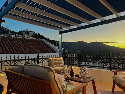 a living room with a couch and a table on a balcony at Symi Blue Studio in Symi