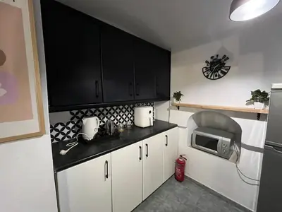a kitchen with white cabinets and a black counter top at Symi Blue Studio in Symi