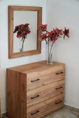 a dresser with a mirror and a vase with flowers on it at Anna's Apartments in Kremasti