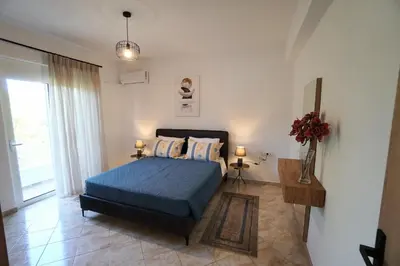 a bedroom with a blue bed and a window at Anna's Apartments in Kremasti
