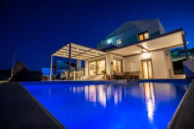 a villa with a swimming pool at night at Nostos Villa in Kalathos