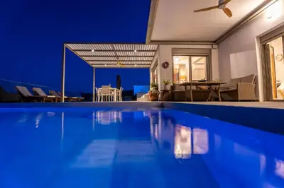 a villa with a swimming pool at night at Nostos Villa in Kalathos