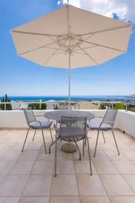 a table and chairs with an umbrella on a balcony at Nostos Villa in Kalathos