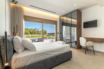 a bedroom with a large white bed and a television at Emerald & Ruby Villas in Asgourou