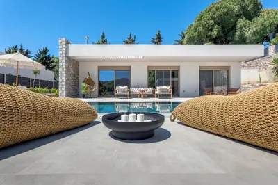 a villa with a pool with two chairs and a fountain at Emerald & Ruby Villas in Asgourou
