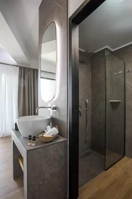 a bathroom with a sink and a glass shower at 3K Rodo Rooms in Faliraki