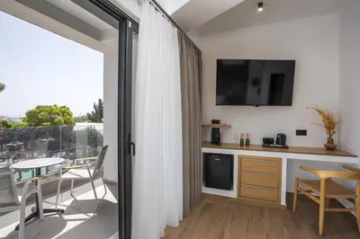 a room with a balcony with a table and a television at 3K Rodo Rooms in Faliraki