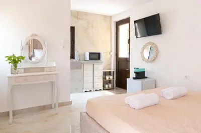 a white bedroom with a bed and a mirror at Majestic Marble Retreat in Rhodes Town