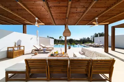 an outdoor patio with a table and chairs and a pool at Luna Llena Villas in Afantou