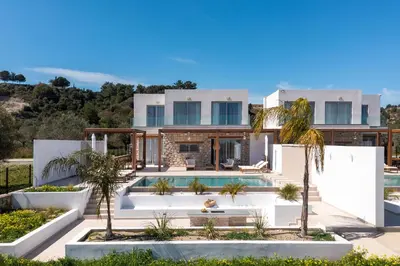 a villa with a swimming pool in front of a house at Luna Llena Villas in Afantou