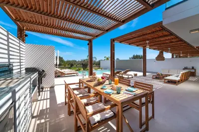 an outdoor patio with a wooden table and chairs at Luna Llena Villas in Afantou