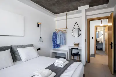 a bedroom with a bed and a table with a chair at ArmoniKon Pool Villas in Asgourou